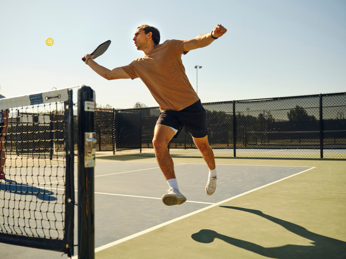 Man leaping across kitchen while playing pickleball