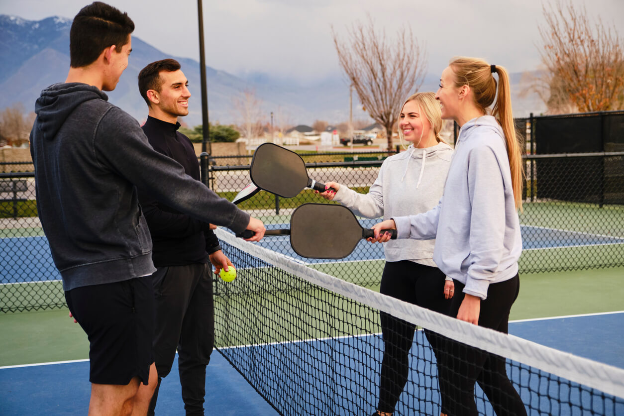 Two men and two women at the net after a pickleball match